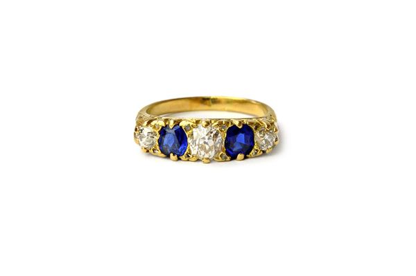 A gold, diamond and sapphire five stone ring, mounted with three cushion shaped diamonds and with two cushion shaped sapphires and with four pairs of