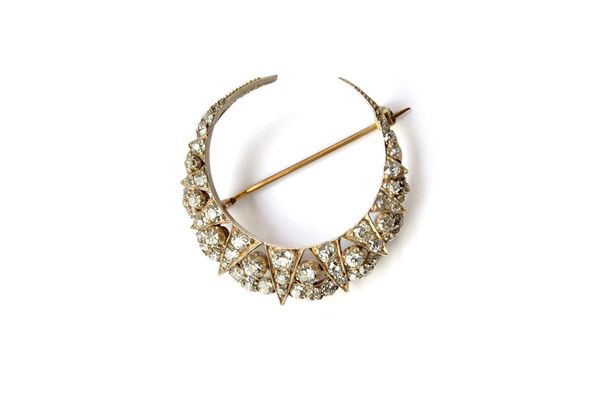 A Victorian gold backed and silver set diamond brooch, designed as a crescent, mounted with cushion shaped diamonds. Illustrated.