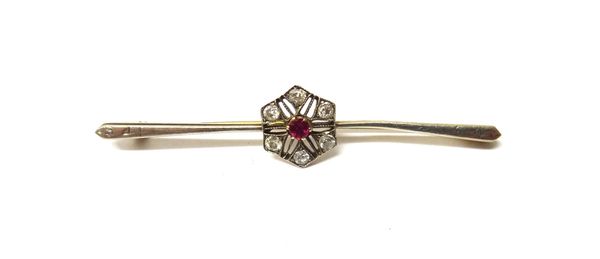 A gold, diamond and ruby set cluster bar brooch, in a pierced hexagonal design, mounted with the circular cut ruby at the centre, with a surround of s