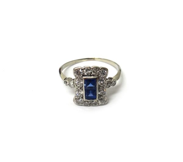 A sapphire and diamond ring, in a rectangular panel shaped design, mounted with two square cut sapphires to the centre, within a surround of twelve cu