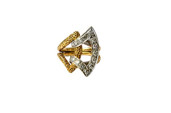 A gold and diamond set ring, in a stylized double buckle design, mounted with circular cut diamonds and having a textured finish, in the 1960's style,