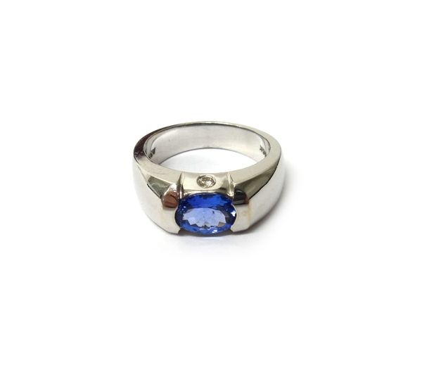 A white gold, tanzanite and diamond set three stone ring, mounted with an oval cut tanzanite, each side of the mount set with a circular cut diamond,