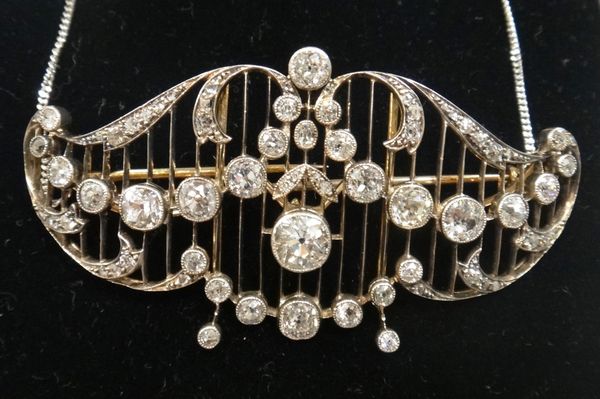 A diamond set brooch cum necklace front, in a scroll and foliate pierced openwork undulating design, mounted with cushion shaped diamonds and with the