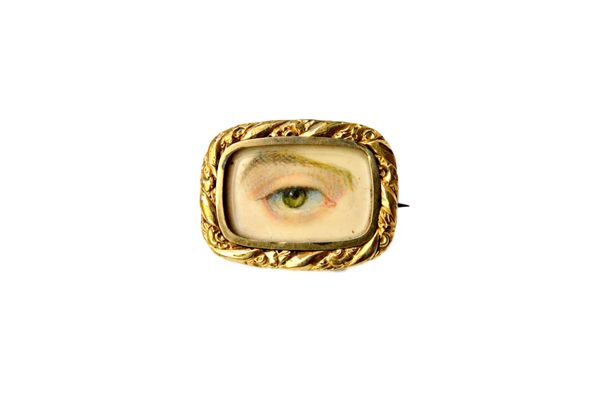 An early Victorian gilt metal mounted eye miniature brooch, of rectangular form, within a decorated border, engraved to the back M.RYE. Illustrated.