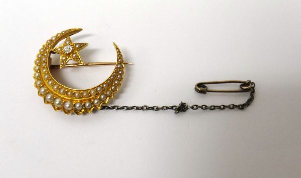 A gold, diamond and seed pearl set brooch, designed as a crescent enclosing a star, the star centred by the cushion shaped diamond, otherwise mounted