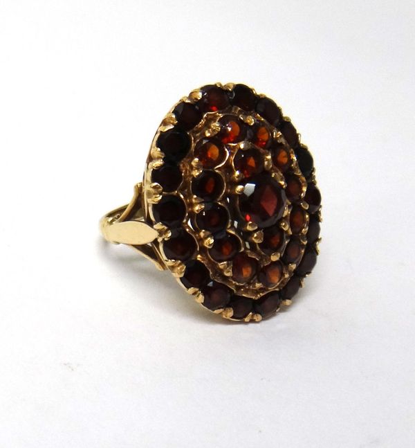 A 9ct gold and garnet set oval cluster ring, mounted with circular cut garnets, London 1962, ring size N and a half.