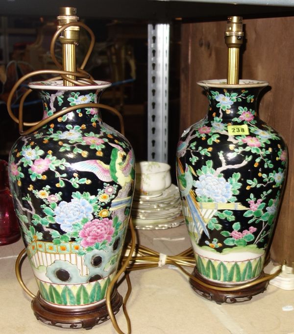 A pair of Oriental ceramic lamp bases decorated with flowers on a black background. (2)  S3M