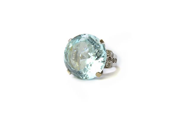 A white gold, aquamarine and diamond ring, circa 1940, claw set with the large circular cut aquamarine at the centre, between diamond set and scroll p