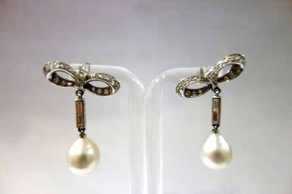 A pair of cultured pearl and diamond set pendant earrings, each comprising; an ovoid cultured pearl drop, with a circular cut diamond set bow shaped s