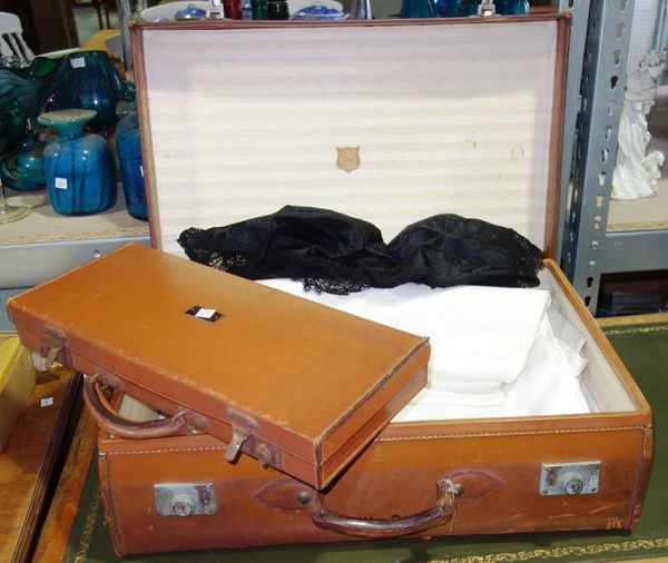 A quantity of linen and two brown leather suitcases. GAL