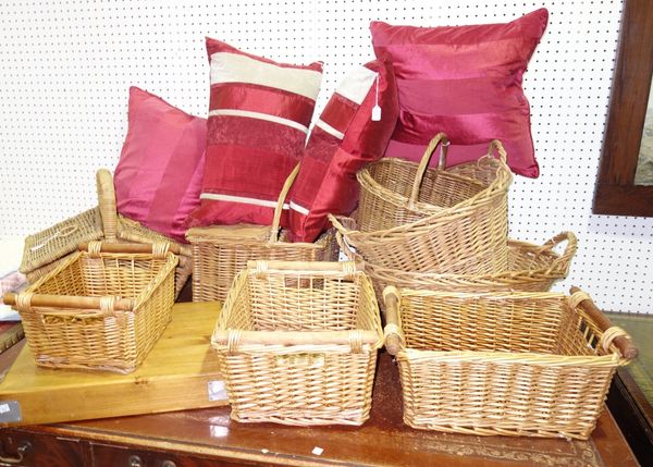 An assortment of wicker baskets, a butcher's block chopping board and four red scatter cushions. GAL