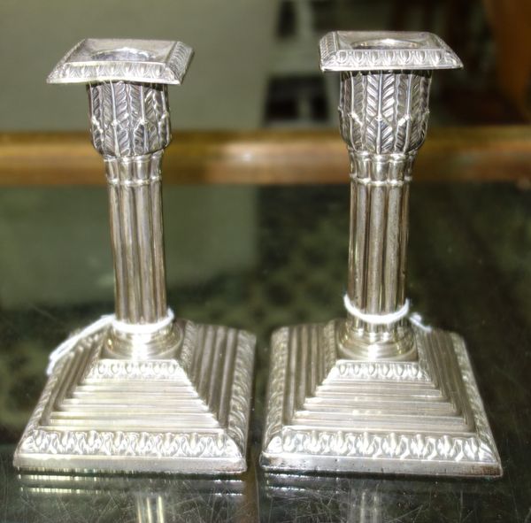 A pair of late Victorian silver candlesticks, each formed as a classical column, on a stepped square base, having decorated borders, London possibly 1