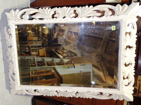 A parcel gilt and cream painted wall mirror, in a swept carved frame, 103cm wide x 77cm high. MIR