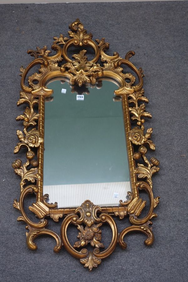An 18th century style gilt framed wall mirror with opposing 'C' scroll upper and lower frieze and foliate carved frame, 60cm wide x 125cm high. MIR