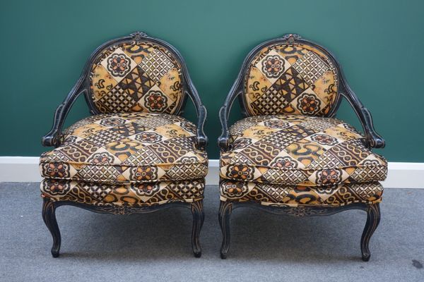 A pair of ebonised French design open arm fauteuils, on serpentine seats and cabriole supports, (2). I6