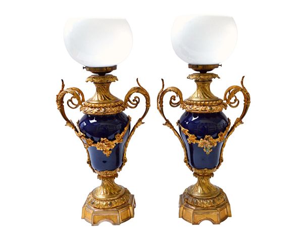 A pair of French porcelain and gilt metal vase lamps, late 19th century, each two handled baluster lamp now adapted to electricity with a dished opaqu