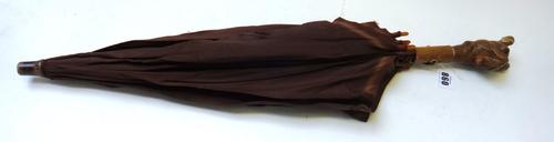 An early 20th century umbrella, the wooden handle carved as a dog's head with articulated mouth, 66cm long, and three silver mounted walking sticks (4