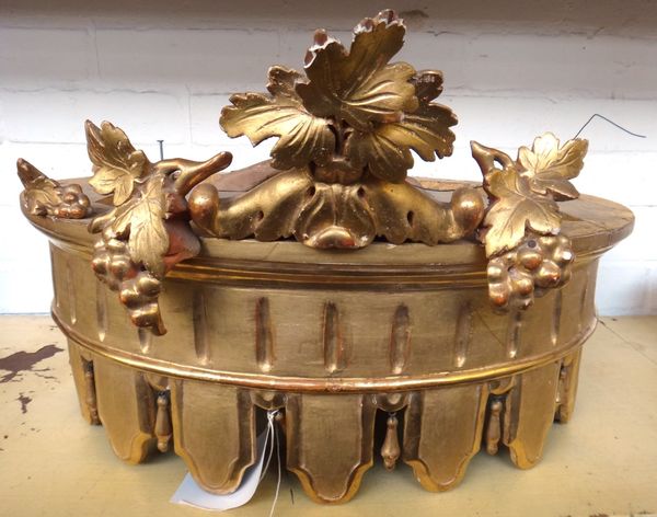 A gilt wood carved half tester coronet, 20th century, with a fruiting vine carved surmount and castellated rim, 56cm wide.Property from the estates of