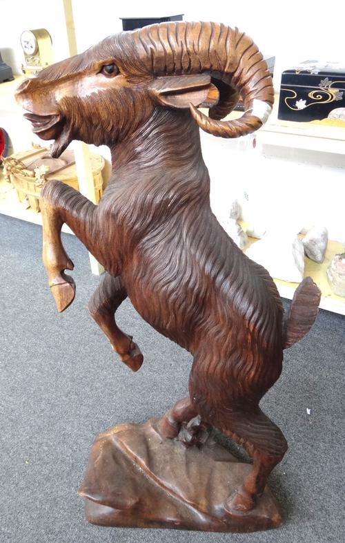 A Continental hardwood model of a mountain goat, 20th century, raised on hind legs atop a naturalistic base, 109cm high. (a.f.)