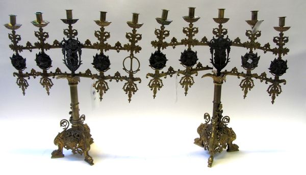 A pair of Continental bronze five branch altar candelabra of Gothic form, the five sconces over two tiers detailed with white metal plaques cast in re