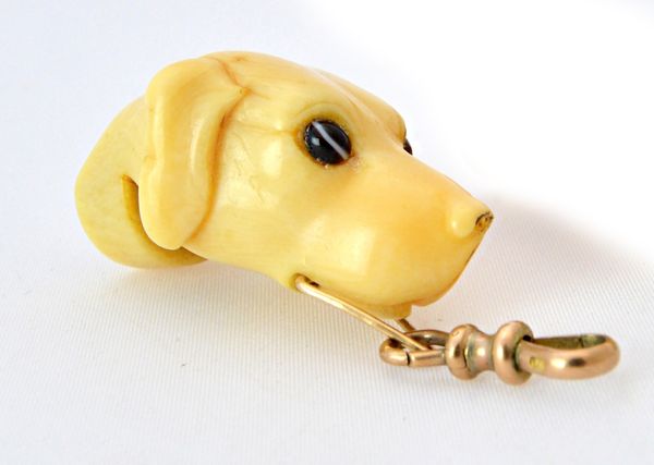 A Victorian ivory novelty whistle carved as the head of a dog, with inset glass eyes, 4.7cm long. Illustrated.