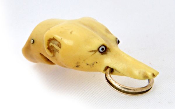 A Victorian ivory novelty whistle carved as the head of a dog, with inset glass eyes, 5cm long. Illustrated.