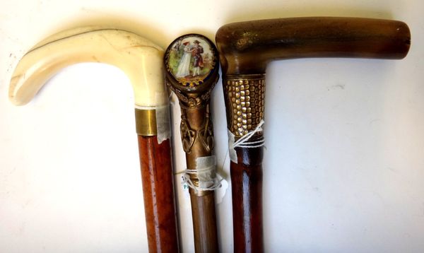 A Victorian walking cane with carved ivory handle, 81.5cm long, a horn handled bamboo walking stick, and one further walking stick with a porcelain pl