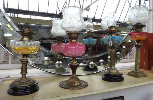 A Victorian oil lamp with a painted blue glass reservoir, fluted brass column and an ebonised pottery base, another with relief cast brass foot detail