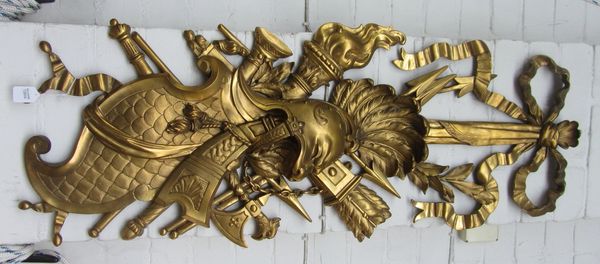 A pair of gilt bronze wall appliques, 20th century, each relief cast with a bow surmount over military crested helmets and a variety of weapons, 97cm