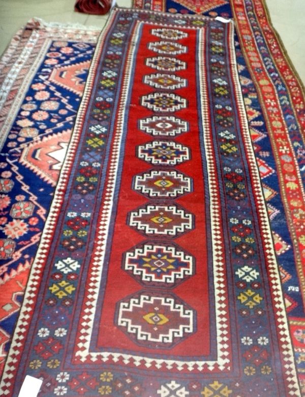 A Shiraz runner, Caucasian, the plain madder field with eleven single hooked guls, a green border with arrowhead and flowerhead design, 274cm x 100cm.