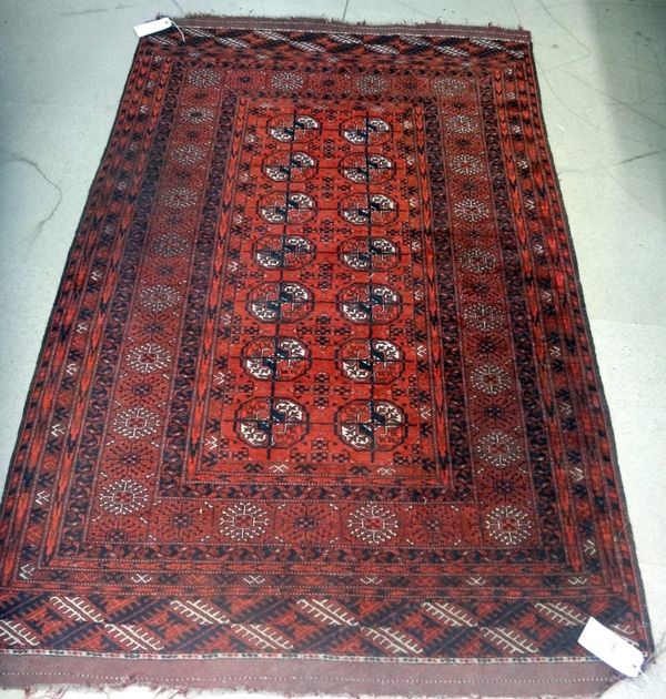 A Tekke Turkmen rug, the madder field with two columns of seven guls, supporting crosses, a sunburst border, 204cm x 132cm.