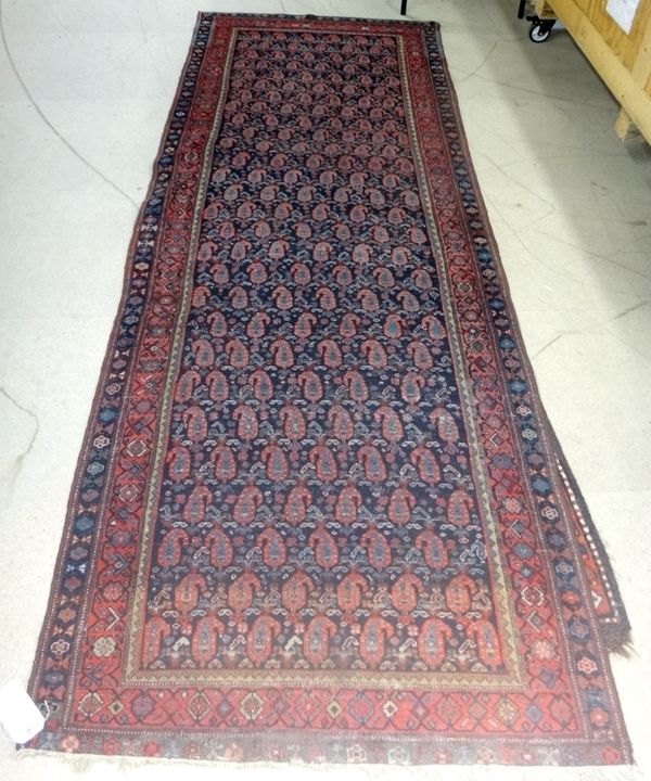 A Fereghan runner, Persian, the dark indigo field with rows of madder botehs, minor botehs, a madder flower border, 313cm x 113cm.