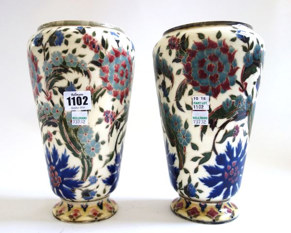 A pair of Zsolnay Pecs pottery oil lamp bases, circa 1900, each decorated with Persian flowers against a cream ground, with blue printed marks, 24cm h