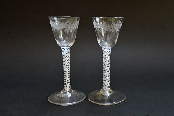 A pair of engraved wine glasses, circa 1765, with rounded funnel bowls engraved with birds in branches, raised on double series opaque twist stems, 15