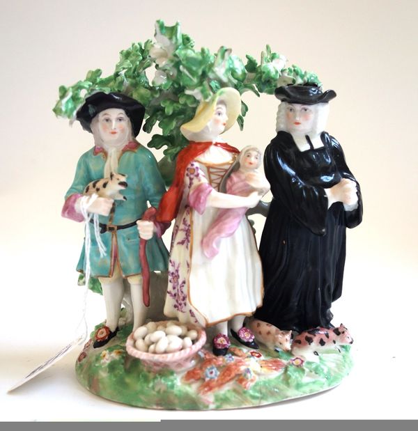 A Derby `Tithe Pig' group, late 18th century, of traditional form, the three characters standing before a tree with a basket of eggs, two piglets and
