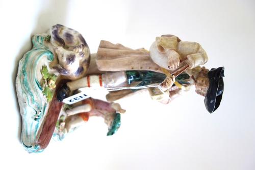 A Chelsea figure group, circa 1760, modelled as a bagpiper standing with one foot on a plank, a seated boy and sleeping dog at his feet, (a.f), 20cm.