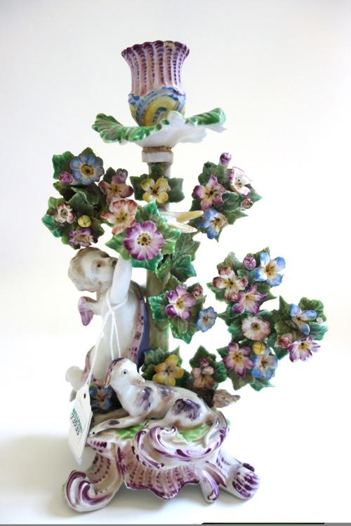 A Bow candlestick group, circa 1765, modelled as Cupid reaching up towards a bird perched in flowering branches, a recumbent dog and a quiver of arrow