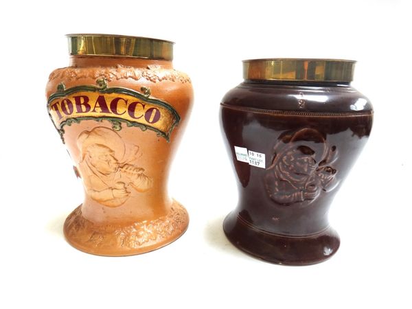 A stoneware tobacco jar and metal cover, 19th century, titled 'TOBACCO' and relief moulded with a gentleman smoking a pipe (23.5cm high) and one furth