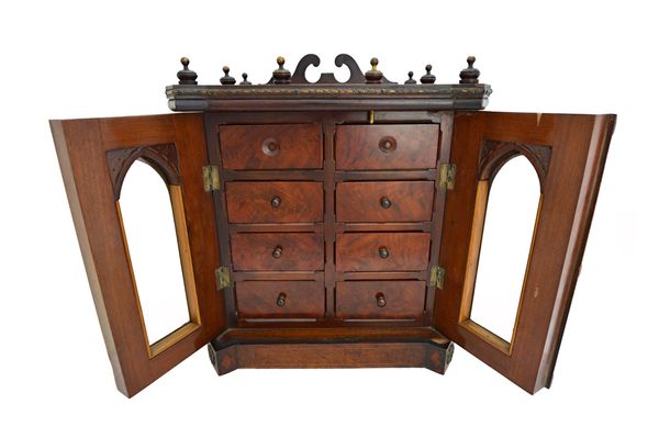 A late 19th century mahogany and rosewood table top cabinet, the pair of Gothic bevelled glass doors enclosing eight drawers, on plinth base, 40cm wid