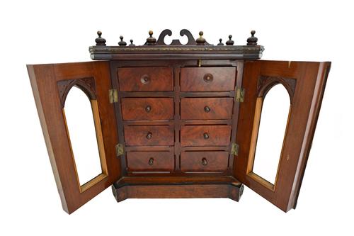 A late 19th century mahogany and rosewood table top cabinet, the pair of Gothic bevelled glass doors enclosing eight drawers, on plinth base, 40cm wid