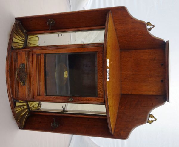 A late 19th century oak hanging corner smoker's cupboard, with glazed door over drawer flanked by mirrored panels, 36cm wide.