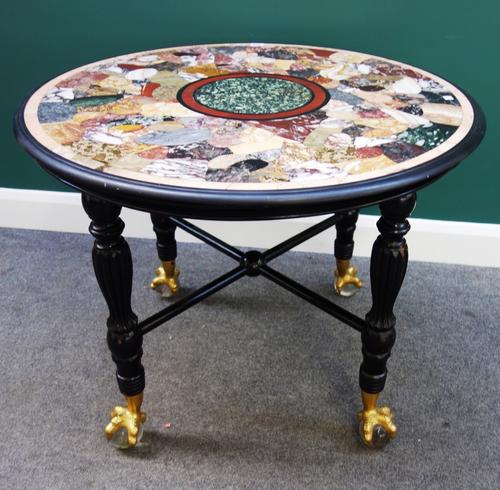A late 19th century centre table, the circular specimen marble inset top on four ebonised baluster reeded supports, resting on four gilt metal claw an
