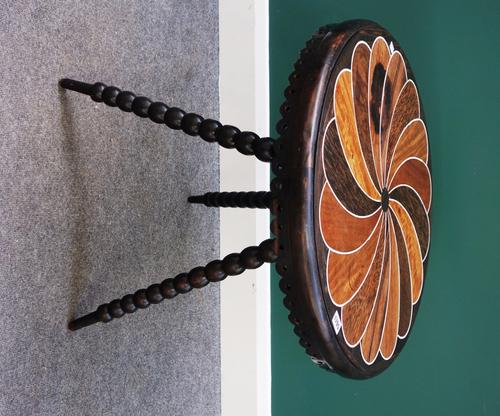 A 19th century Ceylonese occasional table, the circular bone and specimen wood inlaid top over carved and pierced frieze, on three bobbin turned suppo