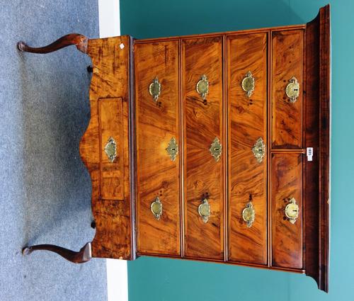 An early 18th century cross banded walnut chest of two short and three long graduated drawers, the associated stand with single frieze drawer, on cabr