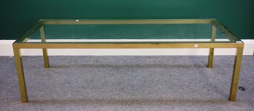A 20th century coffee table, with rectangular glass inset top on four square tubular lacquered brass supports, 59cm x 138cm.