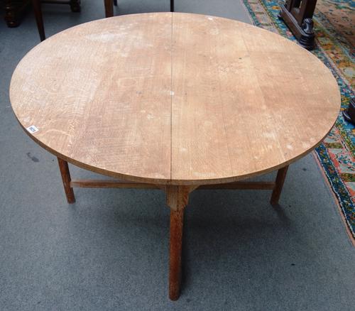 In the manner of Heal & Sons, an early 20th century limed oak circular table, on turned supports, united by 'X' frame stretcher, 115cm wide.
