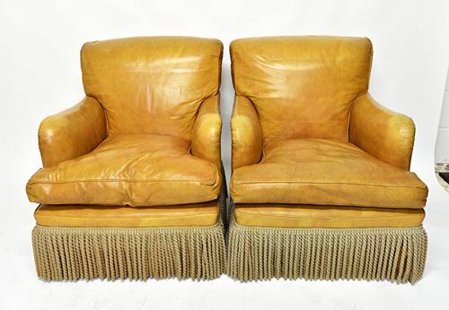 In the manner of Howard and Sons a pair of brown leather upholstered easy armchairs on tapering square supports.  Illustrated