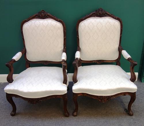 A pair of 18th century style French carved stained beech open arm fauteuils, with serpentine seats, on cabriole supports, (2).