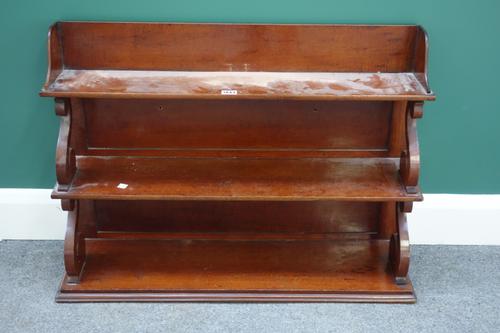 'Freeman'; an early Victorian mahogany hanging waterfall three tier bookshelf on 'S' scroll supports, with paper trade label to reverse, 82cm wide, to