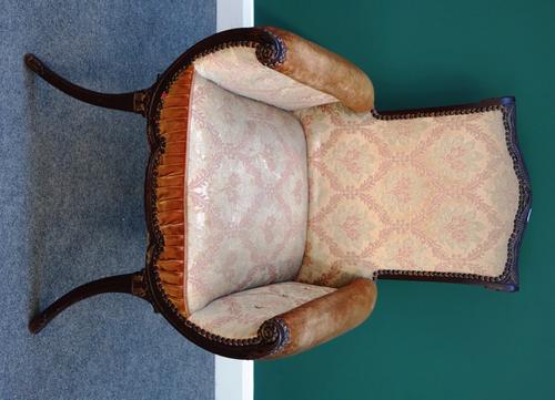 An Empire style parcel gilt mahogany armchair, with shaped back and inswept arms, on splayed supports.